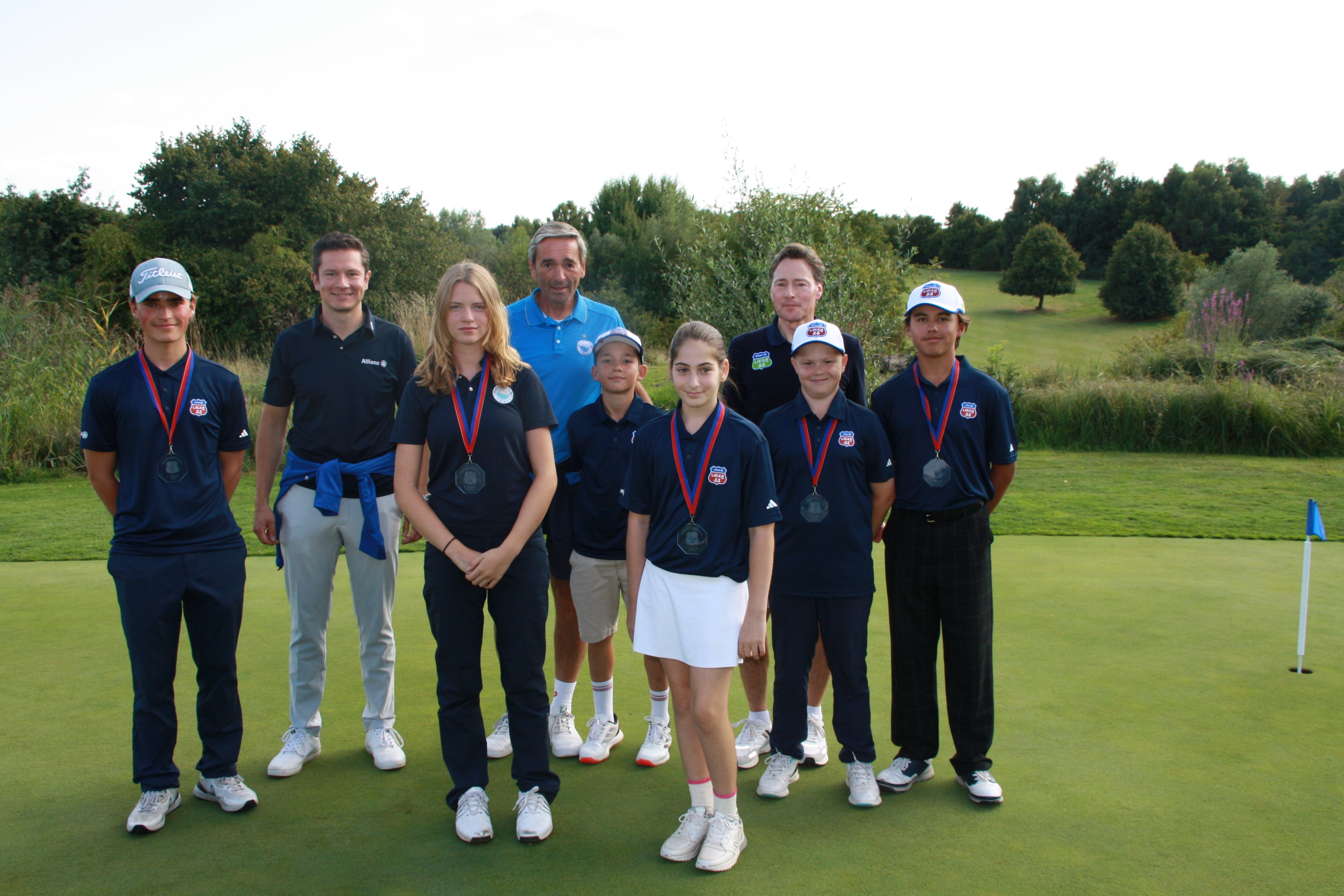 Gruppenfoto von Golferinnen und Golfern auf einem Puttinggrün